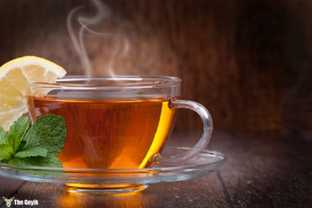 Cup of tea with mint and lemon on a wooden background